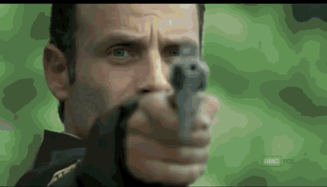a close up of a man holding a gun with a blurred background that says a & m on it