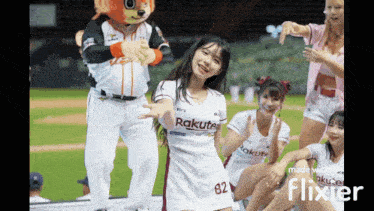 a group of cheerleaders are dancing in front of a mascot wearing a rakuten shirt