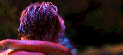 a man and a woman are hugging each other in a dark room with purple lights behind them .