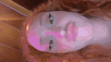 a close up of a woman 's face with a pink glow
