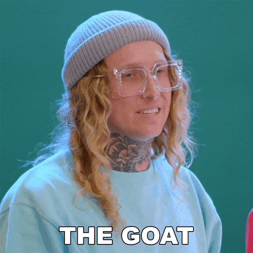 a woman wearing glasses and a beanie has the word goat on her shirt