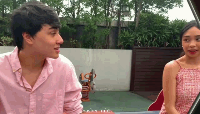 a man in a pink shirt is talking to a woman in a red top