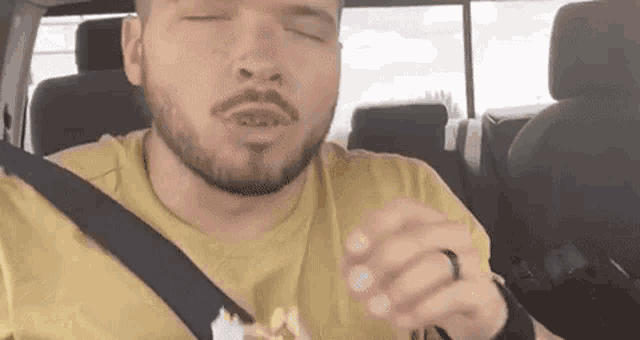 a man with a beard is sitting in a car eating popcorn .