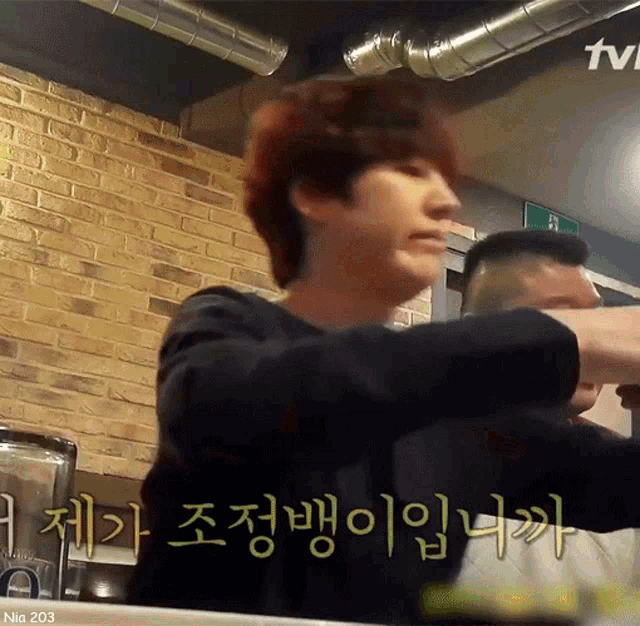 a man sitting at a table with a tv logo in the corner