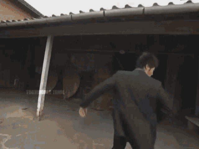 a man in a suit is standing in front of a building that says tokyo music tami
