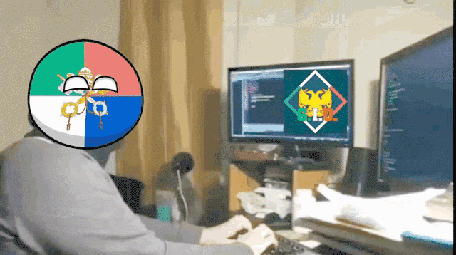 a man sitting in front of a computer with a cartoon ball on his head that says ' a ' on it