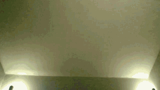 a man wearing headphones looks up at the ceiling of a room