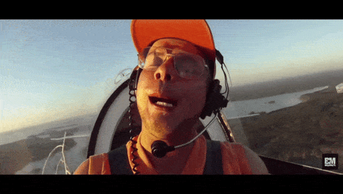 a man wearing a hat and glasses is flying in a plane