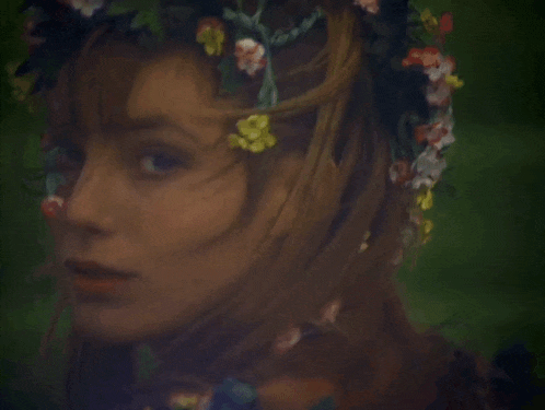 a woman with a flower crown on her head looks at the camera