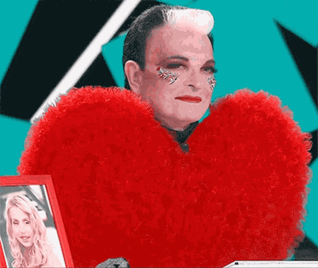 a man is wearing a red heart shaped costume and holding a picture of a woman