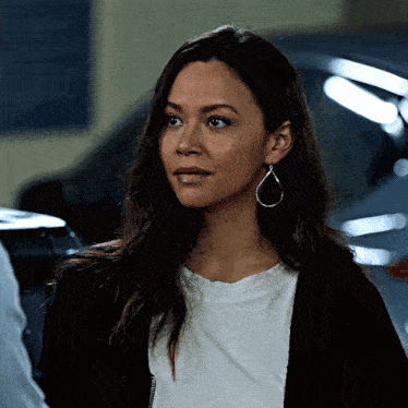 a woman wearing a white shirt and hoop earrings