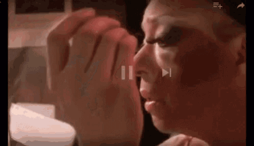 a close up of a person applying makeup to their face in a video .