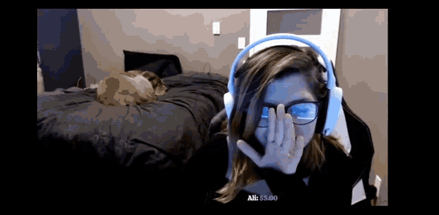 a woman wearing headphones and glasses is covering her face