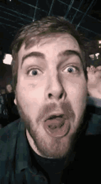 a man with a beard is sticking his tongue out and making a funny face .