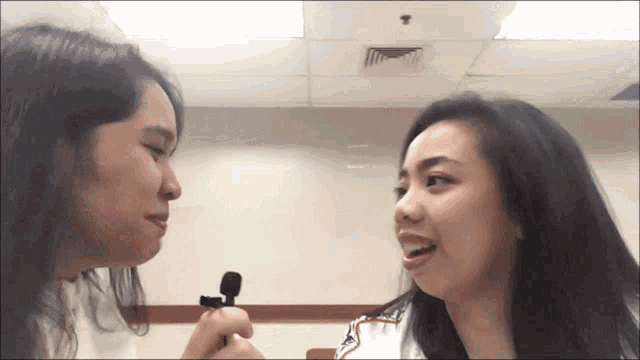 two women are looking at each other and one is holding a small microphone