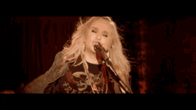 a blonde woman is singing into a microphone while holding a guitar