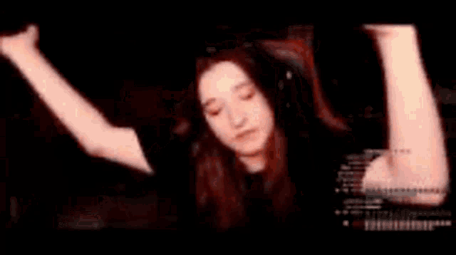 a girl is sitting in a chair with her hands in the air and smiling .