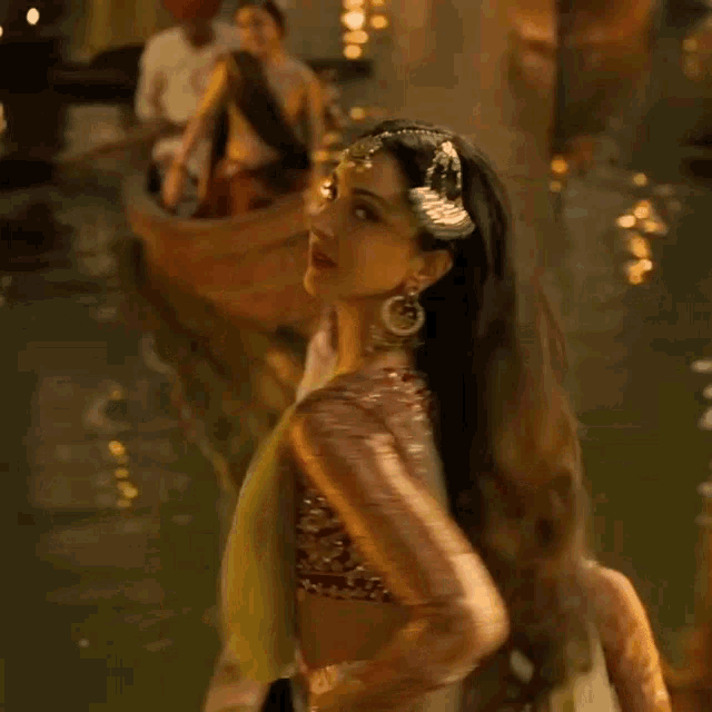 a woman in a traditional indian dress is standing in the water with other women .