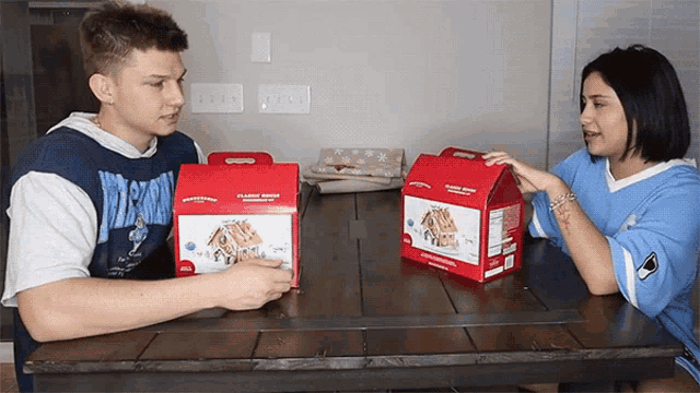 a man and a woman are sitting at a table with gingerbread houses