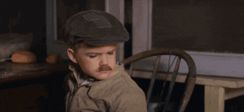 a young boy wearing a hat and a fake mustache