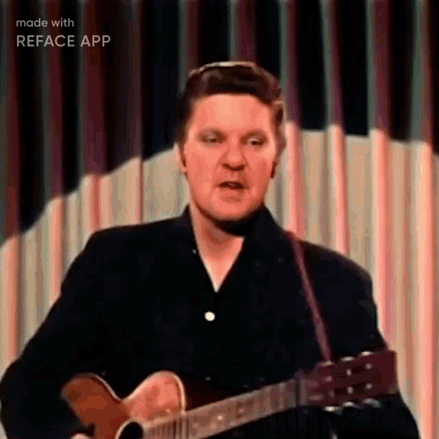 a man is playing a guitar on a stage and singing .