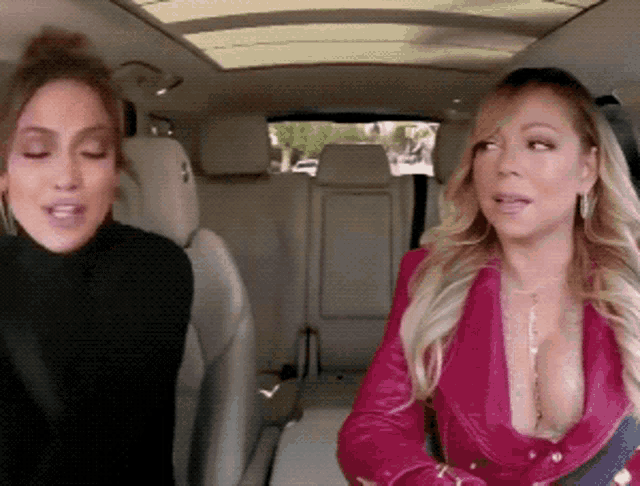 two women are sitting in the back seat of a car talking