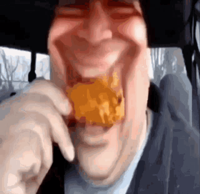 a close up of a man eating a piece of fried food