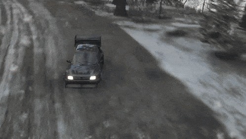 a car is driving down a snowy road with trees in the background