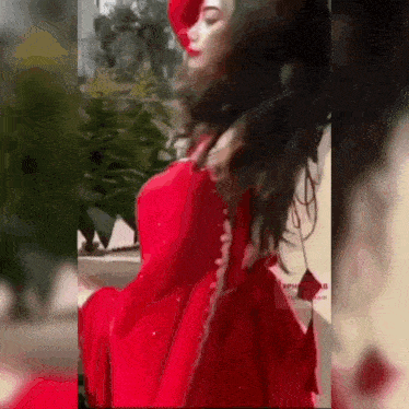 a woman in a red dress and hat is standing in front of a building .