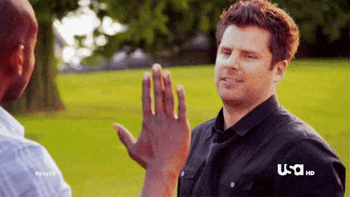 a man in a black shirt is giving a high five to another man