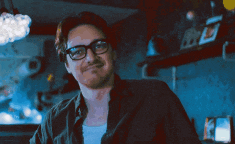 a man wearing glasses and a black shirt smiles