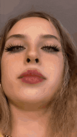 a close up of a woman 's face with long lashes and red lips .