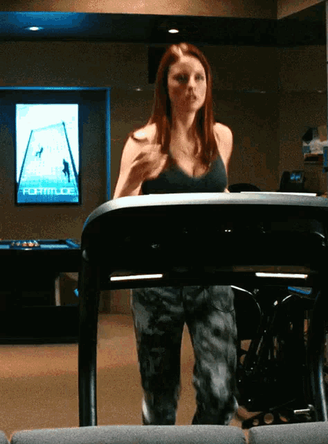 a woman is running on a treadmill in front of a sign that says formitude
