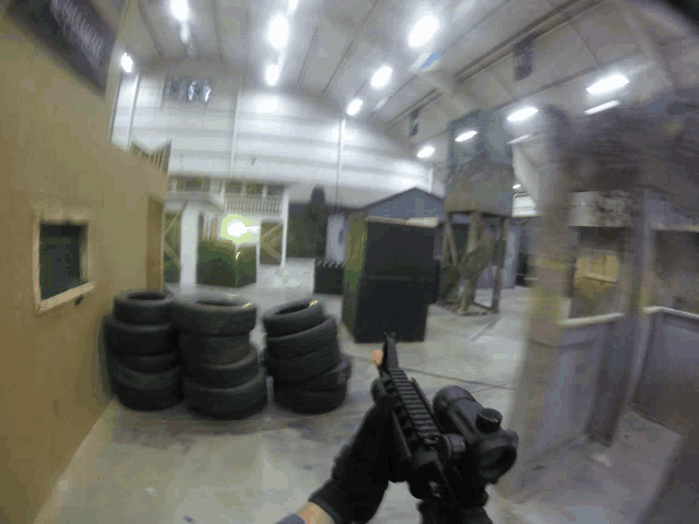 a person holding a rifle in a room with tires and a sign that says ' assault rifle ' on it