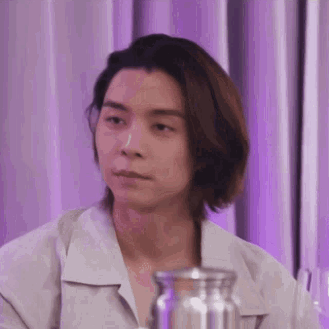 a young man with long hair is sitting at a table .