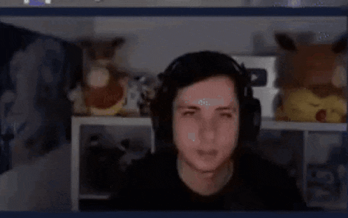 a man wearing headphones is making a funny face while sitting in front of a computer screen .