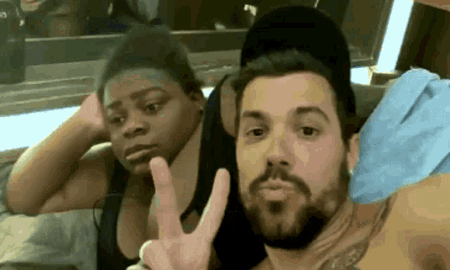 a man and a woman are posing for a photo and the man is giving a peace sign
