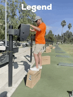 a man in an orange shirt is standing on a box in front of a sign that says legend on it
