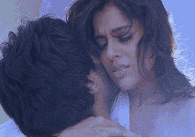a man and a woman are hugging each other and the woman has a sad look on her face