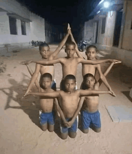 a group of young boys are kneeling down and making a star shape with their arms .