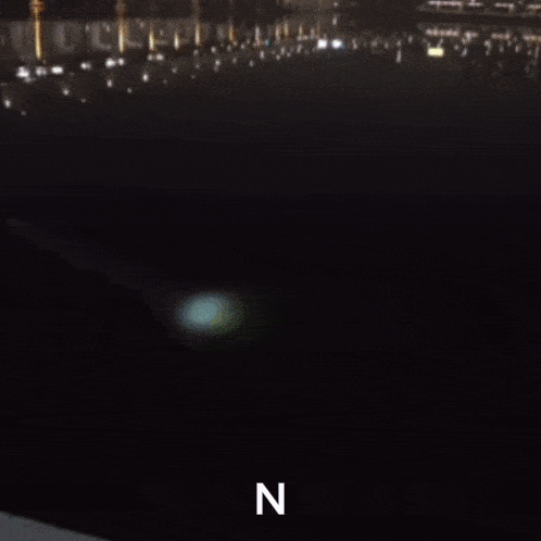 a blurry photo of a person standing in front of a city at night