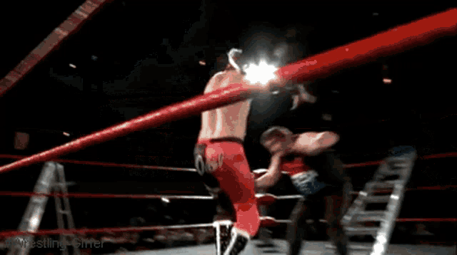 two men are wrestling in a ring with a ladder between them