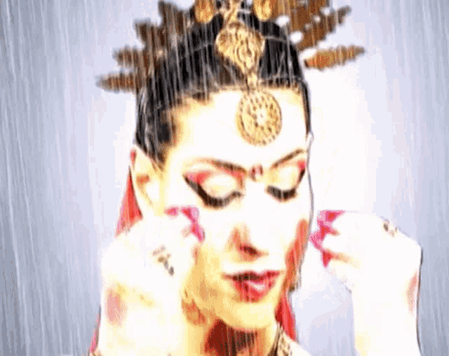 a woman with a crown on her head is covering her ears with her hands .