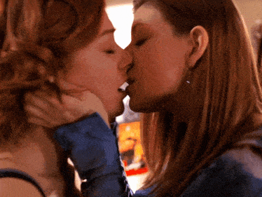a close up of two women kissing with a blurred background