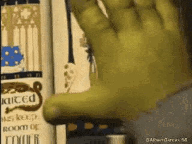 shrek 's hand is reaching out towards a book on a bookshelf .