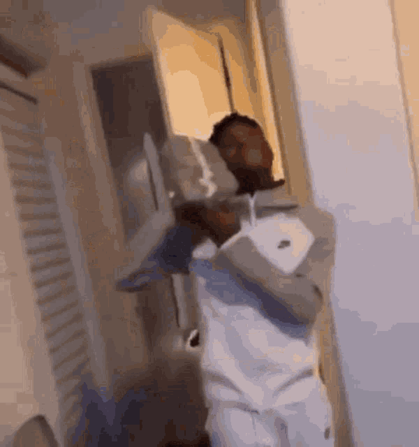 a man in a white nike jacket is standing in a room holding a statue .