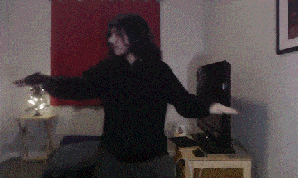 a man in a black hoodie is dancing in front of a television