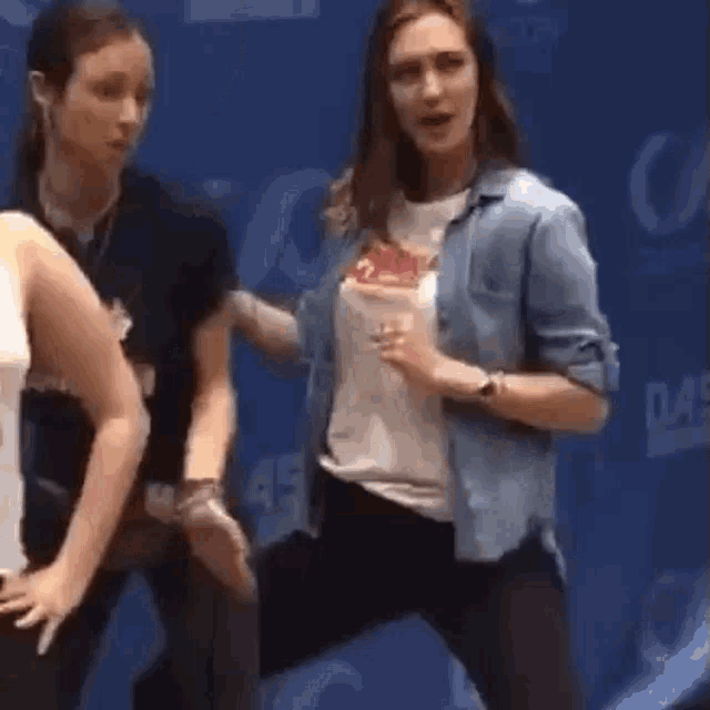 a group of women are dancing in front of a blue background .