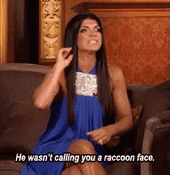 a woman in a blue dress is sitting on a couch and says he was n't calling you a raccoon face