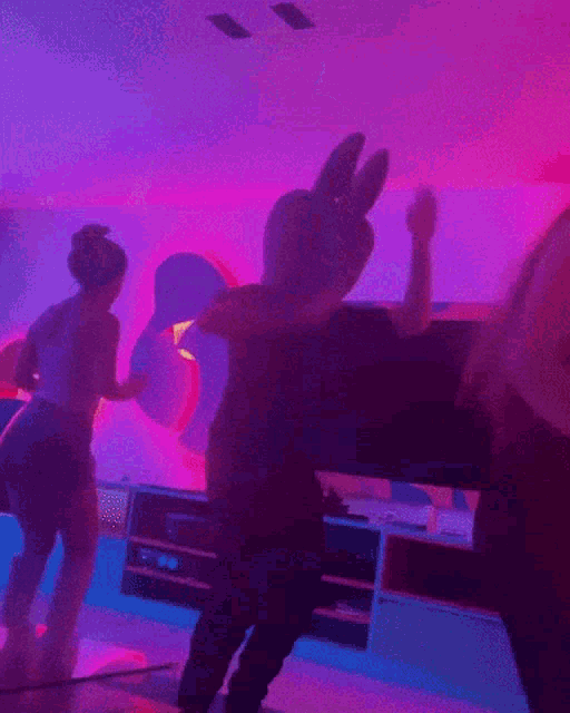 a person wearing a teddy bear costume is dancing in front of a pink wall